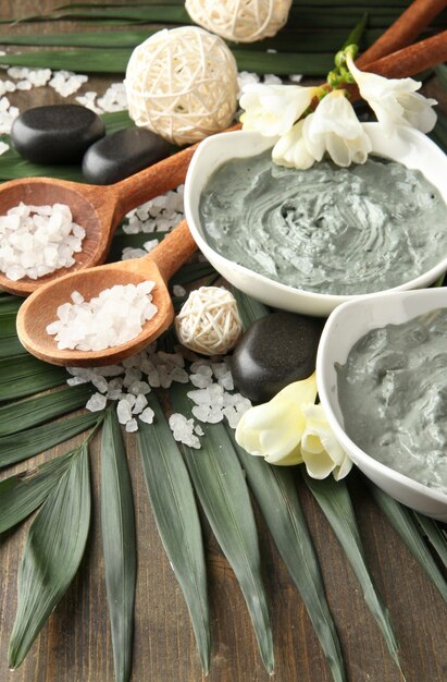 Photo composition with cosmetic clay for spa treatments on palm leaf background