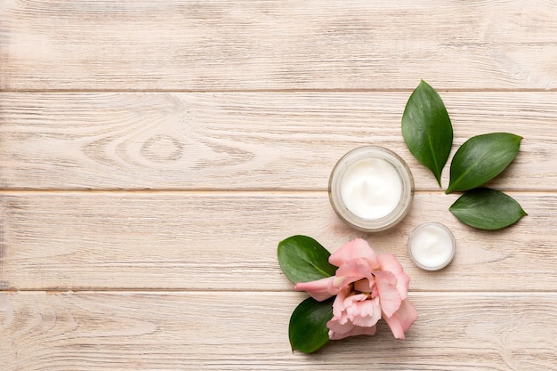 Composition with cosmetic products and beautiful roses on wooden background Copy space flat lay