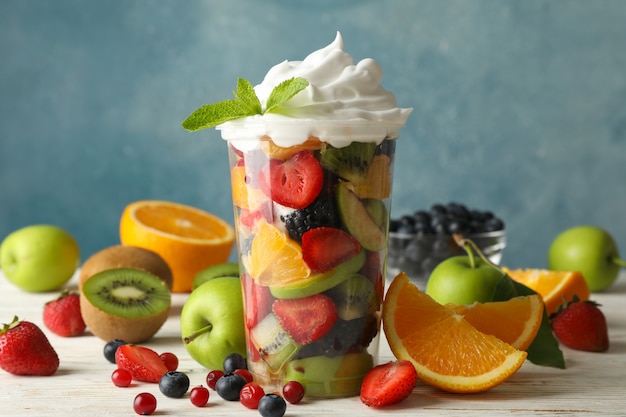 Composition with cup of fresh fruit salad on wooden