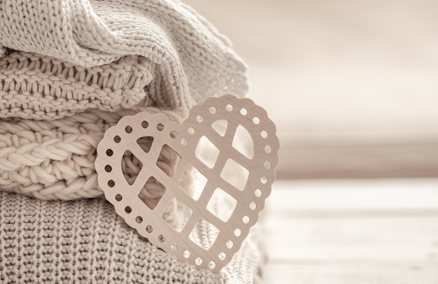 Composition with a decorative heart on the background of neatly folded warm clothes. Valentine's day concept.