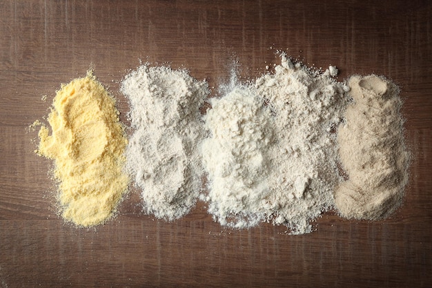 Composition with different types of flour on wooden table