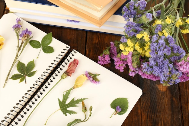 Composition with flowers and dry up plants on notebook on wooden background