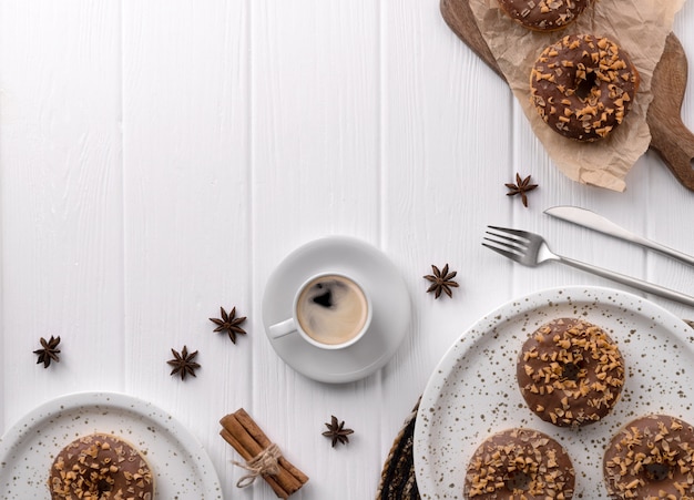 Composition with glazed donuts on a plate on white wooden table