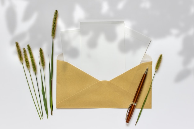 Composition with golden envelope white cards pen decorative green plants and shadow overlay