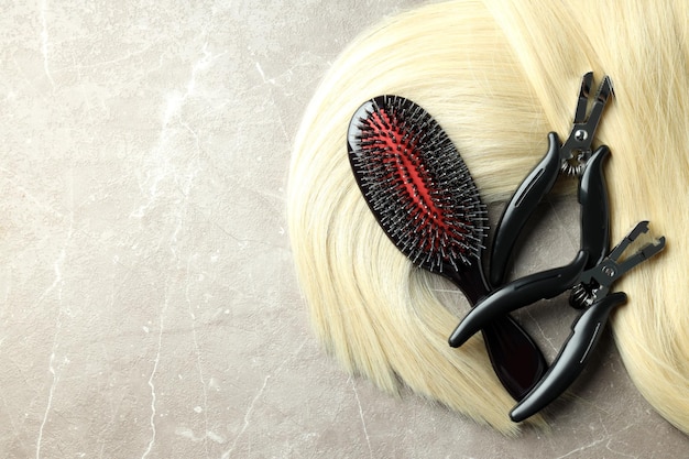 Composition with hair extension accessories on gray textured background