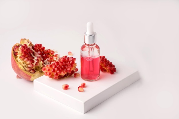 Composition with natural cosmetic oil and pomegranate on light background. High quality photo