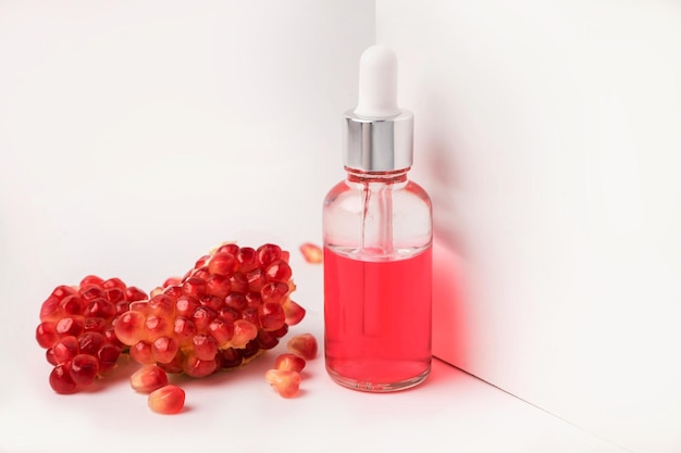 Composition with natural cosmetic oil and pomegranate on light background. High quality photo