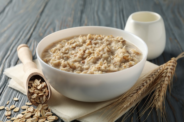 Composition with oatmeal porridge on wooden wall. Cooking breakfast