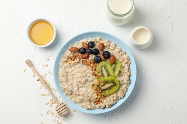 Composition with oatmeal with fruits on white wall