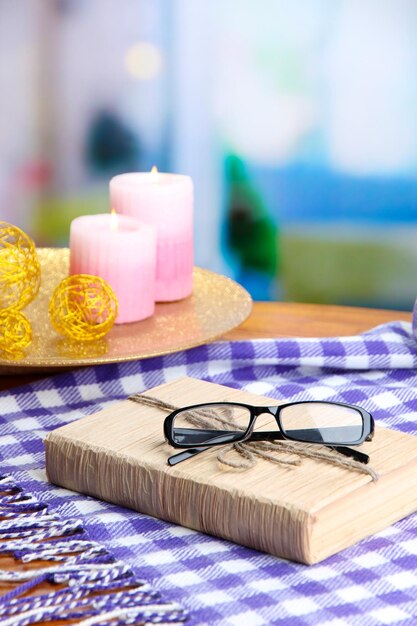 Composition with old book eye glasses candles and plaid on bright background