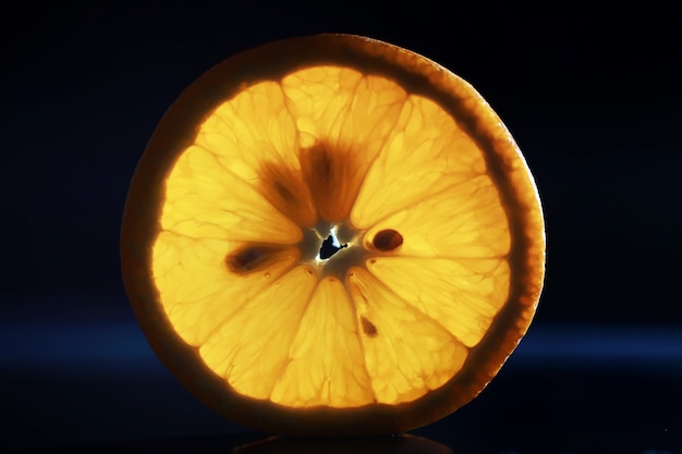 Composition with orange and grapefruit slices on a black background. A slice of orange with back light on a black background with water drops. Juicy orange on a table.