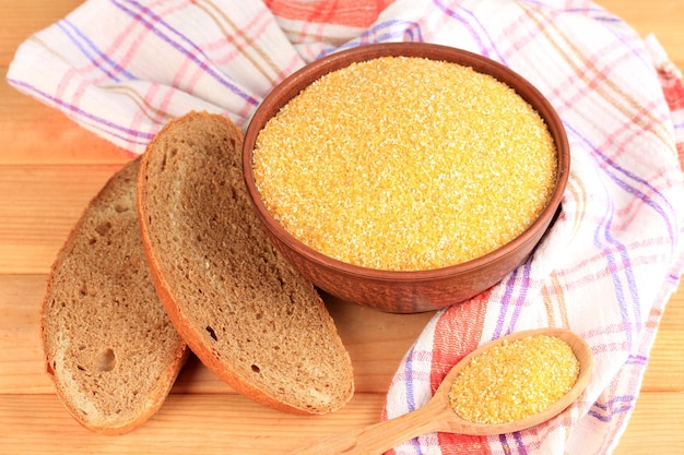 Composition with raw chopped corn in bowl and fresh bread on wooden background