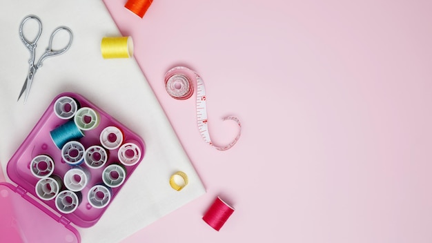 Photo composition with various threads and sewing accessories on pink background top view copy space