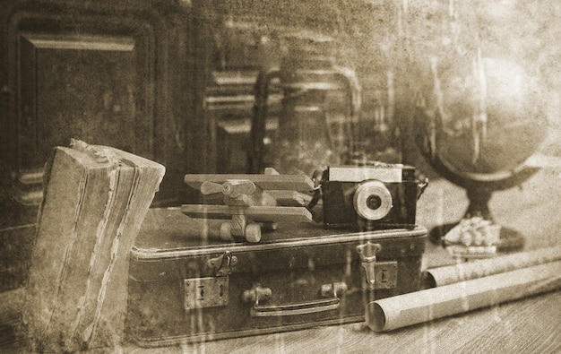 Composition on a wooden floor vintage globe with old leather suitcase with objects for travel