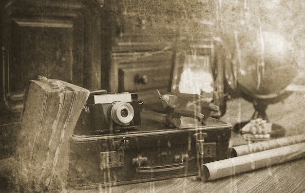 Composition on a wooden floor vintage globe with old leather suitcase with objects for travel