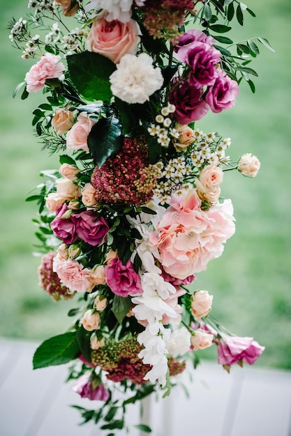 Compositions of flowers decorated with pink hydrangeas roses white carnations and greens which is located stands on arch for wedding ceremony wedding decor