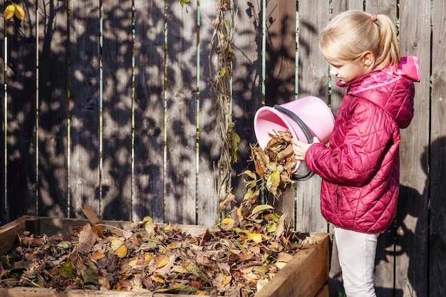 Compost Autumn Leaves Little Girl Kid Throwing Fallen Leaves in Compost bin Recycle Autumn Leaves