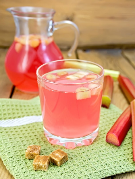 Compote from rhubarb in glassful and jug with sugar on board