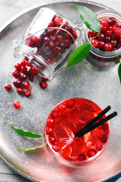 Compote with red currant in glassware on metal tray on wooden table top view