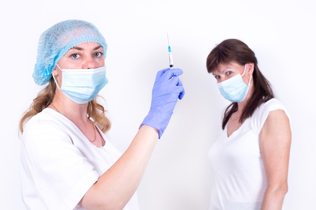 Compulsory vaccination of population female doctor or nurse holds syringe in hand to vaccinate patie...