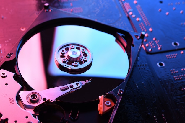 Computer Hard disk drives HDD , SSD on circuit board ,motherboard background. Close-up. With red-blue lighting.