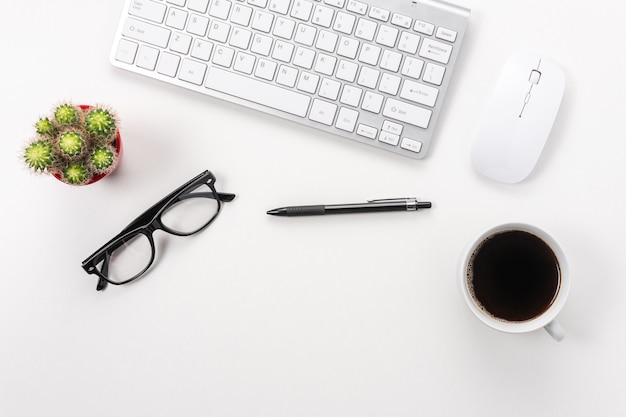 Computer keyboard, office supplies, and coffee cup on white background.