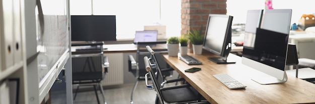 Computer monitors standing on table in empty office. Convenient equipped workplace concept