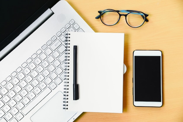 Computer notebook with smartphone notebook message and a pen on working desk in office