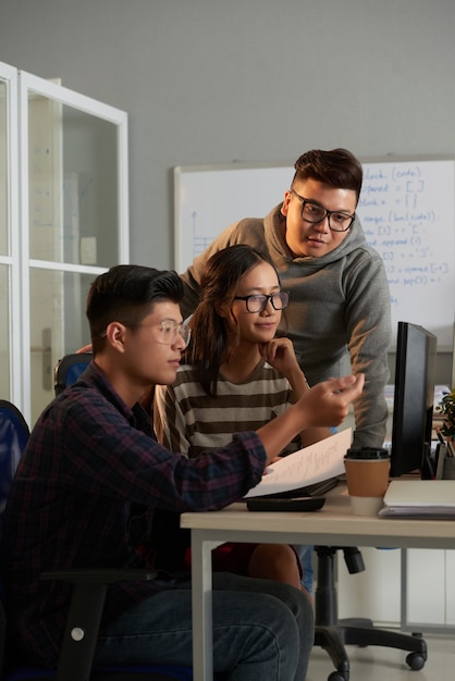 Computer science student explaining his creative idea to friends when they are working on group project