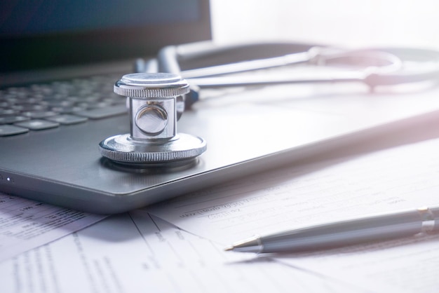 The computer and stethoscope pen lie on the table the concept of health insurance