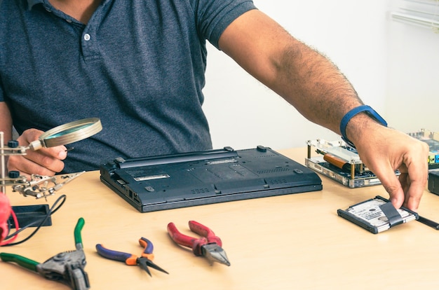 Computer Technician FixingLaptop On Desk. Black man. Work tools.