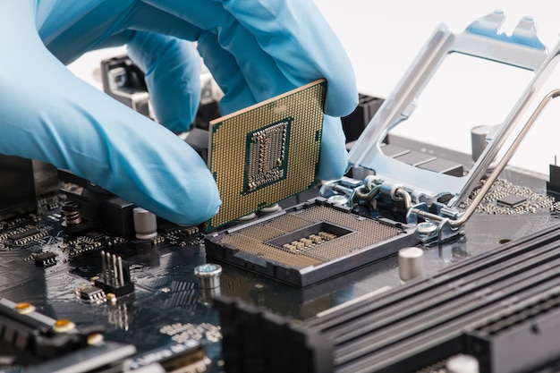 Computer technician wearing blue gloves installing CPU into motherboard close up