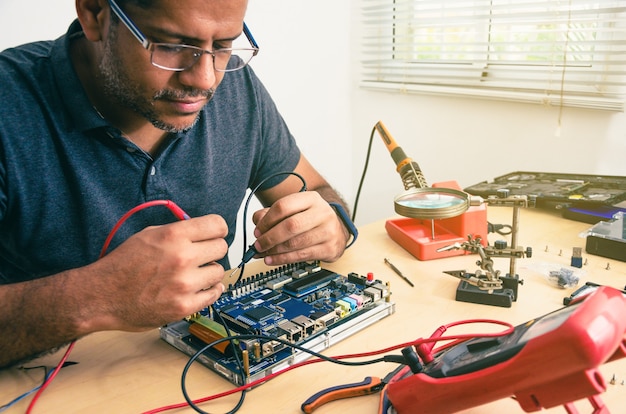 Computer Technician Wearing Glasses, Fixing Laptop On Desk, With Tools Around. Black man. Work tools.