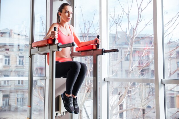 Concentrated attractive young sportswoman working out in gym