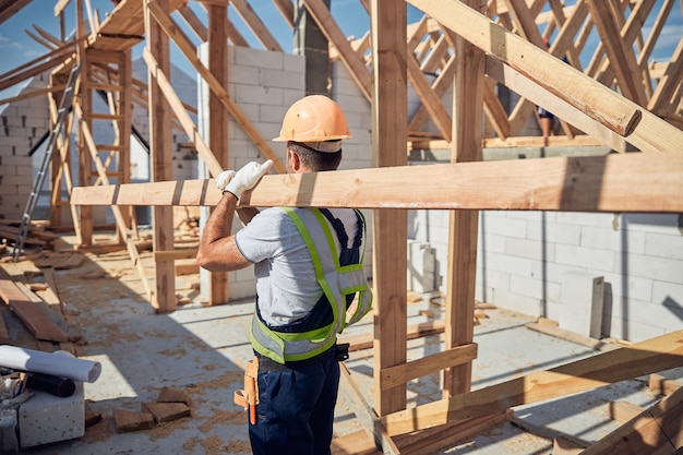 Concentrated brunette man wearing uniform while working on construction site alone