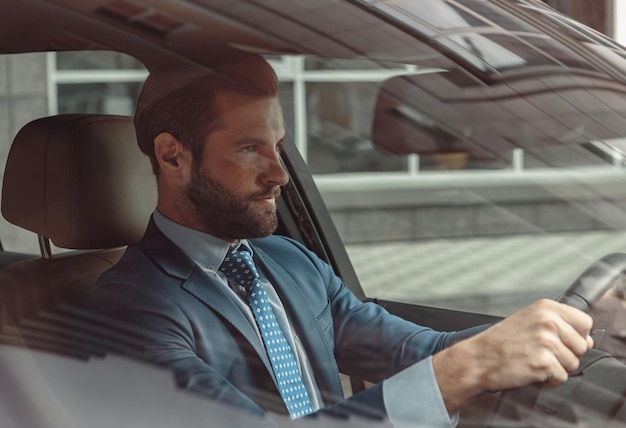 Concentrated confident male in suit traveling by automobile