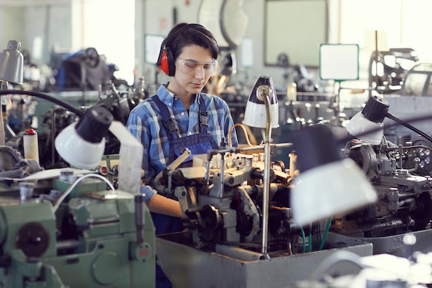 Concentrated female engineer using manual lathe