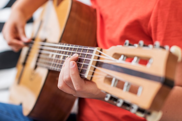 Concentrated girl is practicing with acoustic guitar sit on sofa at home