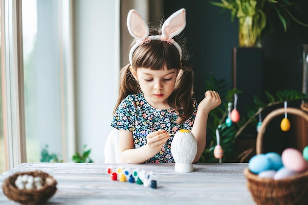 Concentrated little girl painting Easter egg