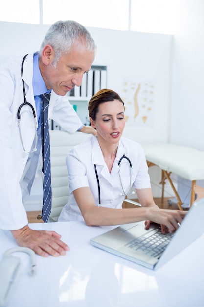 Concentrated medical colleagues discussing and working with laptop