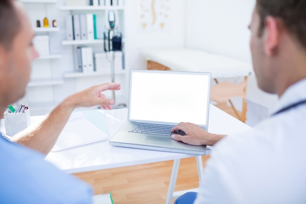 Concentrated medical colleagues working with laptop and pointing the screen