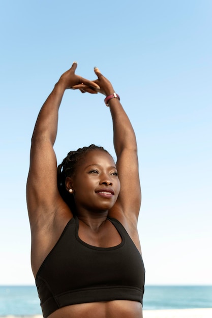 Concentrated positive african american woman in sportswear doing stretching hand