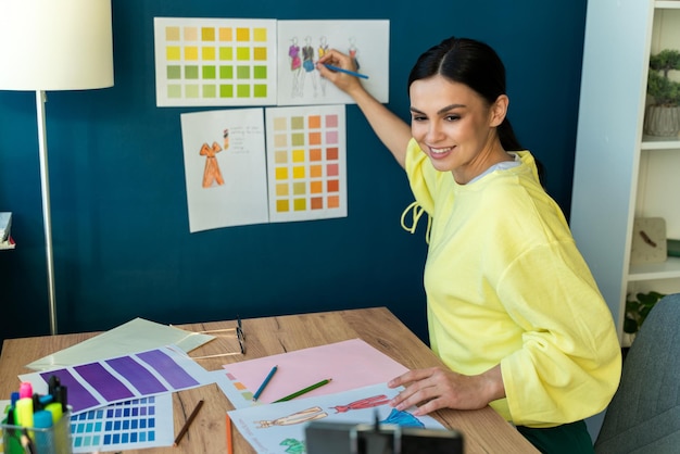 Concentrated professional designer drawing sketches of new design for stylish clothes while sitting in own atelier studio