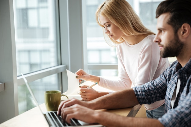 Concentrated two colleagues in office coworking while using laptop