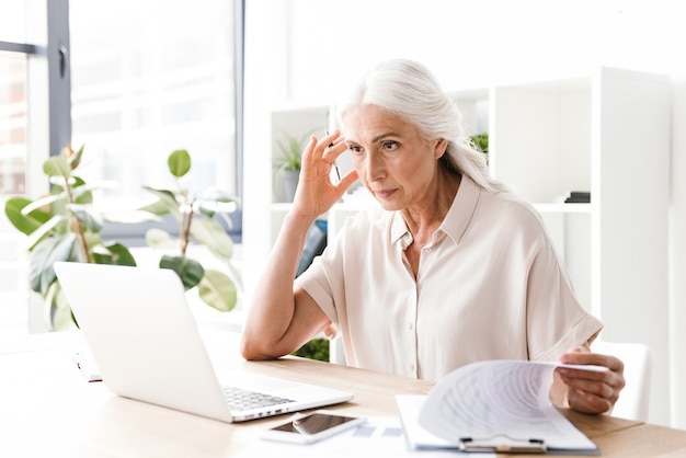 Concentrated woman indoors in office working writing notes.