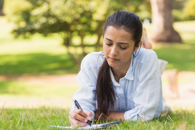 Concentrated woman with book and pen in park