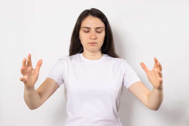 Concentrated woman with closed eyes holds her hands wide meditates