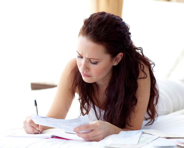 Concentrated woman writing notes in bed