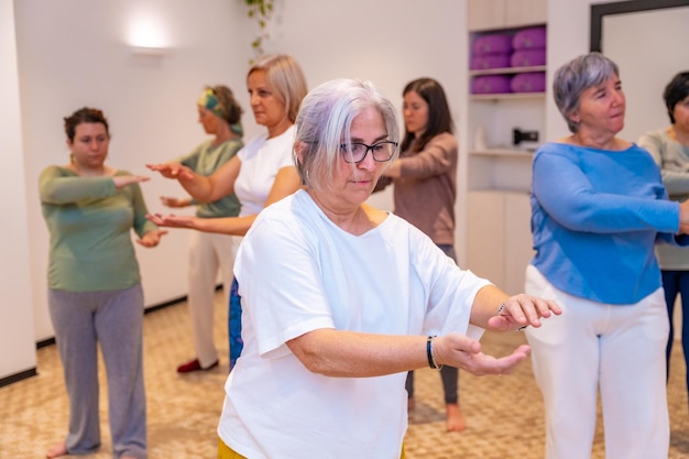 Concentrated women exercising in pairs during qi gong class