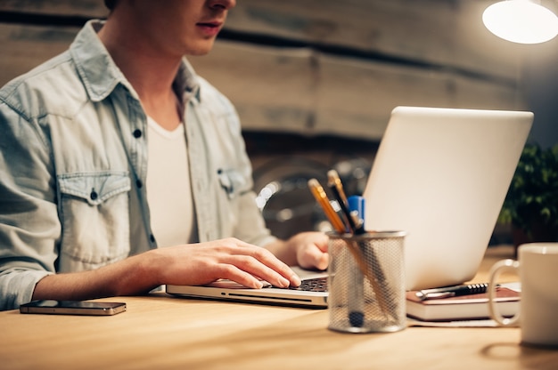 Concentrated on work. Close-up of confident young man working late while sitting at his working place